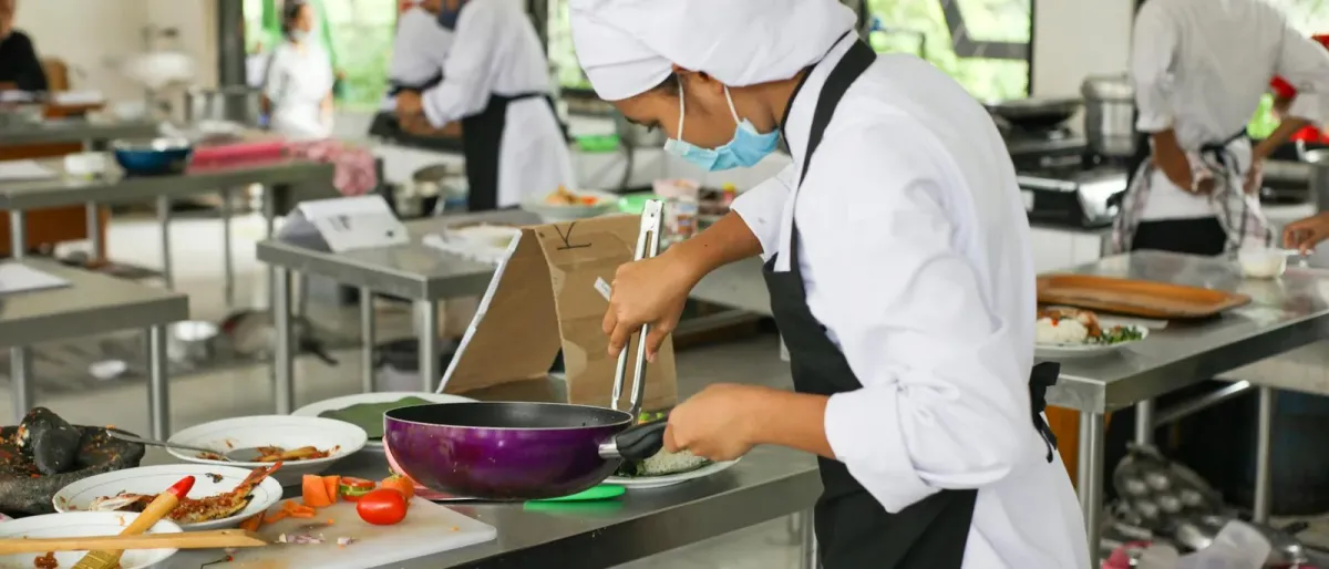 Hospitality students plating dishes in a teaching kitchen during a culinary workshop