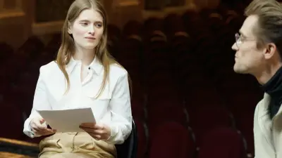 Performers rehearsing on a theatre stage with dramatic studio lighting