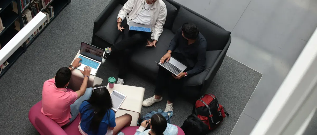 High school students studying together with laptops on library lounge seating, viewed from above