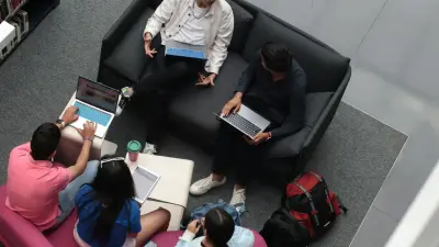 High school students studying together with laptops on library lounge seating, viewed from above