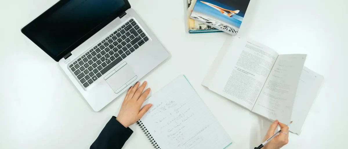 Overhead view of a student planning coursework with a notebook and laptop on a desk