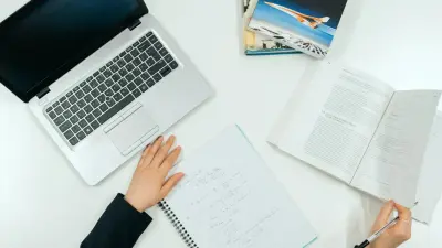 Overhead view of a student planning coursework with a notebook and laptop on a desk