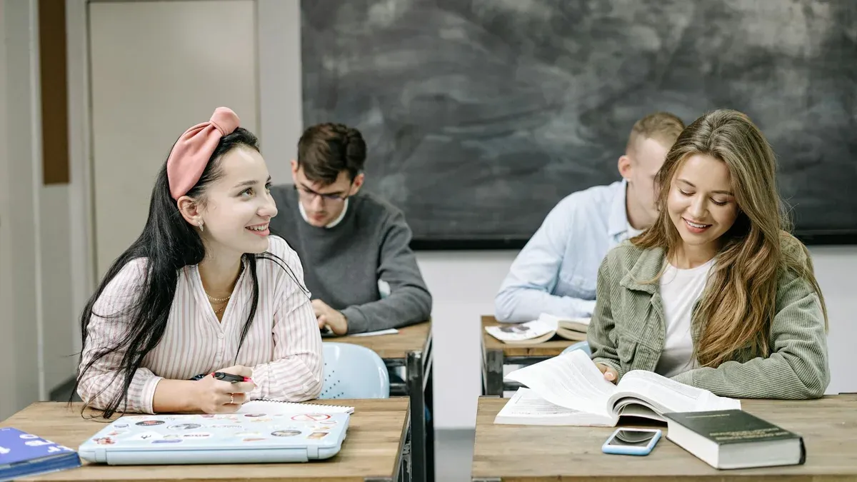 Grade 11 students working at desks in a classroom with a chalkboard backdrop