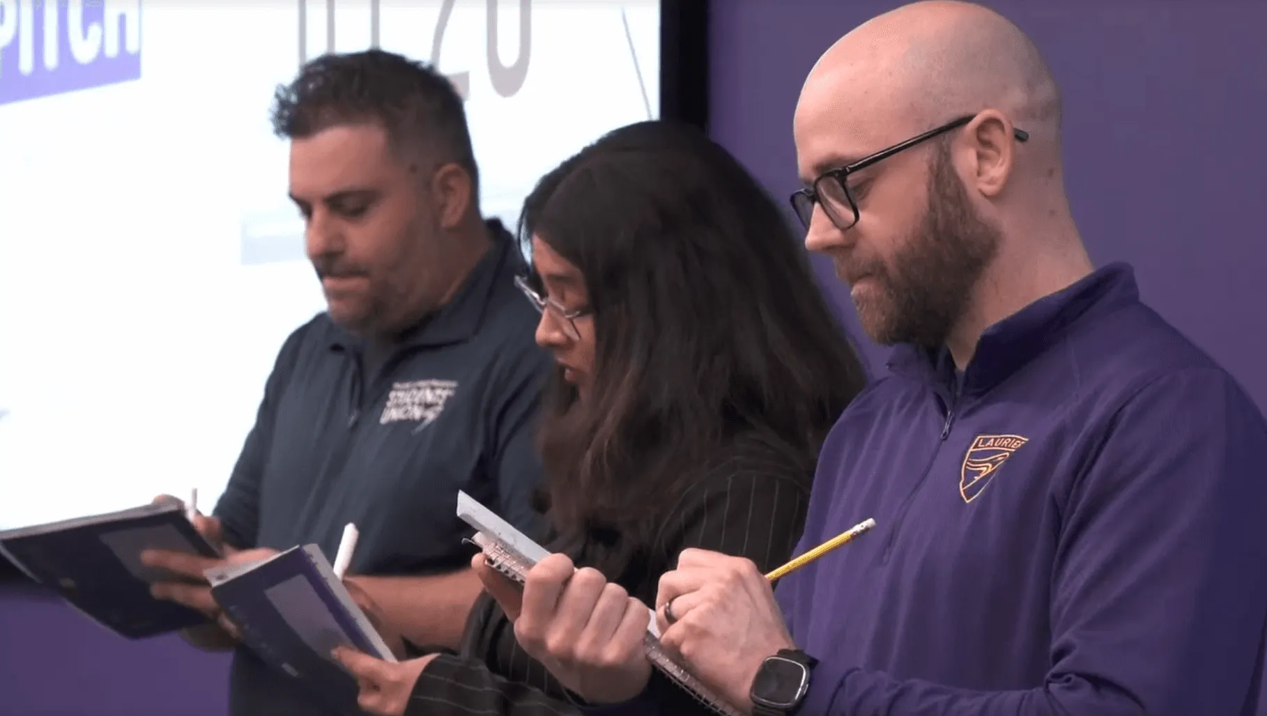 Judges taking notes during the SHSM UX design challenge pitch panel at Wilfrid Laurier University Brantford